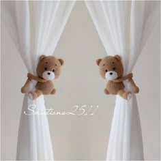 two stuffed teddy bears sitting on top of curtains