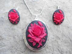 For sale are perfectly detailed, flawless (red rose with a single bud on a black background) cameo pendant silver plated LOCKETS!!!! Gorgeous!!! About 1 3/4" long!!! They hold two photos inside (or keepsakes). The French Earrings are also silver plated, about 1" long and very nice quality!!  They are offered at a reasonable price, make perfect gifts, and are wonderful quality!!!!  and the chain is 22" .925 silver plated 1.2mm snake chain, with a lobster claw clasp!!!! Please do visit my shop!!! Valentine's Day Rose Design Party Jewelry, Rose Red Roses Jewelry For Valentine's Day, Red Rose Design Jewelry For Mother's Day, Red Rose Jewelry For Anniversary, Black Rose Design Party Jewelry, Rose Red Roses Jewelry For Weddings, Elegant Black Jewelry With Rose Design, Rose Red Jewelry With Roses For Wedding, Rose Red Wedding Jewelry With Roses