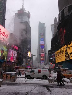 a city street filled with lots of traffic and tall buildings covered in snow during the day