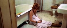 a woman sitting on the floor in front of a bath tub next to a toilet