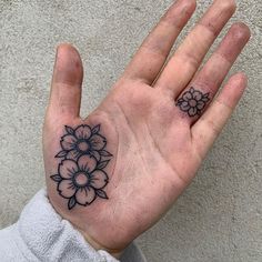 a person's hand with a flower tattoo on the middle of their left palm