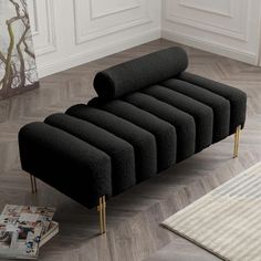 a black couch sitting on top of a hard wood floor next to a white rug