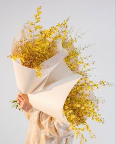 a person holding a bunch of flowers in their hands and covering it with some paper