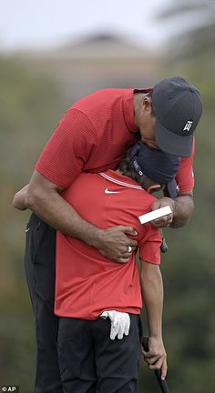 a man holding a small child on top of his shoulder while standing next to another person