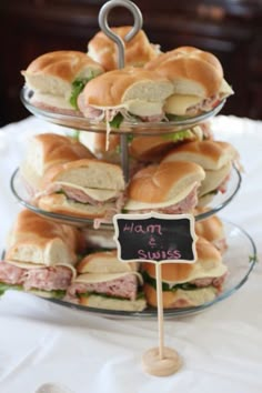 a stack of sandwiches sitting on top of a glass plate next to a chalkboard sign