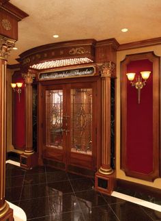 an ornate entry way with red walls and gold trim on the doors, along with black marble flooring