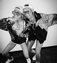 two young women posing for a photo in front of a wall with their arms around each other