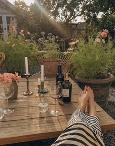 a person sitting at a wooden table with wine glasses and bottles