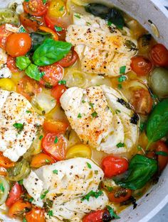 a pan filled with fish and vegetables on top of a stove