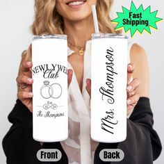 a woman holding two white tumblers with the words newly married and their names on them