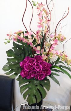 a vase filled with purple flowers on top of a table next to a black chair