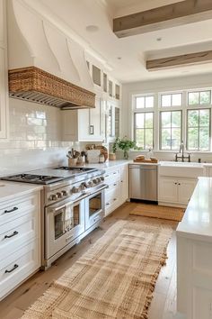 a large kitchen with white cabinets and stainless steel stove top oven next to an island