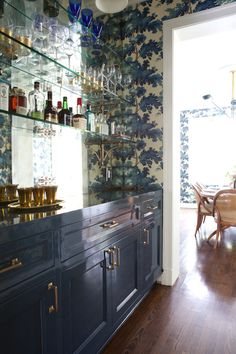 a kitchen with blue cabinets and floral wallpaper on the walls, along with wooden floors