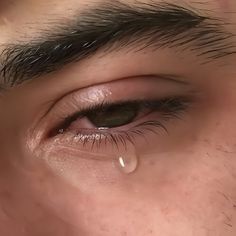 a close up of a man's eye with tears on his face and nose