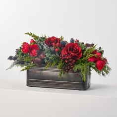 a metal container filled with red flowers and greenery