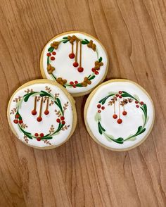 three decorated cookies sitting on top of a wooden table