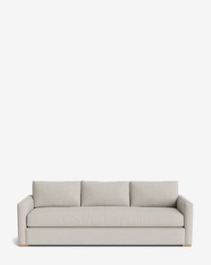 a white couch sitting on top of a wooden floor next to a wall with a light colored