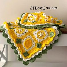 a yellow and white crocheted blanket sitting on top of a window sill