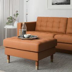 an orange couch and ottoman in a living room with a vase on the coffee table