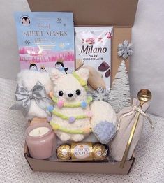 a teddy bear in a gift box with chocolates, candles and other holiday treats