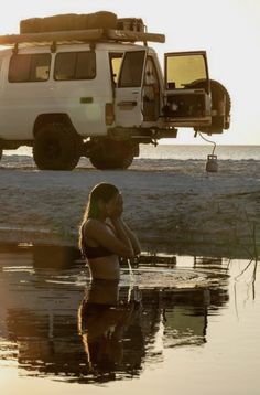 a woman sitting in the water next to a truck