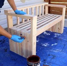 a person in blue gloves painting a wooden bench