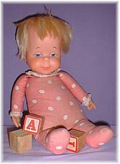 a baby doll with blonde hair and blue eyes sitting next to blocks that spell out the number four