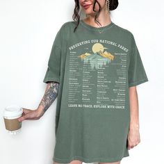 "Welcome to the great outdoors with our vintage retro national parks t-shirt! Featuring a unique and nostalgic design, this t-shirt is perfect for nature enthusiasts, adventurers, and anyone who loves exploring the beauty of America's national parks. This t-shirt showcases all 62 national parks in the U.S., from the iconic Grand Canyon to the majestic Yellowstone, from the breathtaking Yosemite to the serene Great Smoky Mountains, and so many more. The vintage retro style design adds a touch of Graphic Tee Style Short Sleeve Camp Shirt For Outdoor, Green Letter Print Tops For Hiking, Green Tops With Letter Print For Hiking, Vintage Green Tops For Outdoor, Summer Graphic Print Shirt For Outdoor, Short Sleeve Letter Print Shirt For Hiking, Graphic Tee Camp Shirt With Short Sleeves For Outdoor, Green Short Sleeve Top For Hiking, Short Sleeve Camp Shirt With Letter Print For Hiking