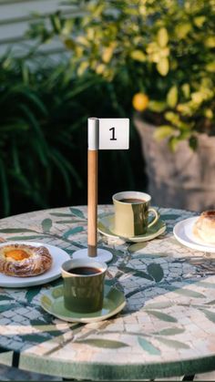 the table is set with two cups of coffee and pastries