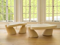 two wooden benches sitting on top of a hard wood floor in front of large windows