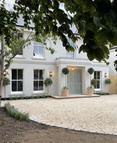 a white house with potted plants in the front yard and gravel path leading up to it