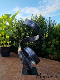 a metal sculpture sitting on top of a tiled floor next to potted planters