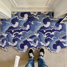 a person standing in front of a blue and white rug with clouds on the floor