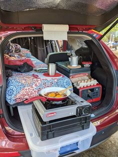 an open trunk with food and drinks in it on the back of a red car