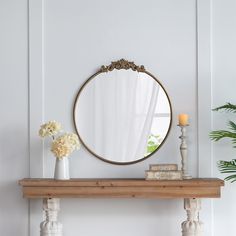 a table with a mirror, candles and flowers on it in front of a white wall