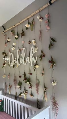 a baby crib with flowers hanging from it's side and the name julia spelled in cursive letters