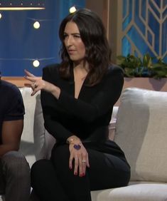 a man and woman sitting on a couch talking to each other