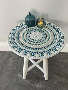 a blue vase sitting on top of a table next to a white and blue mosaic