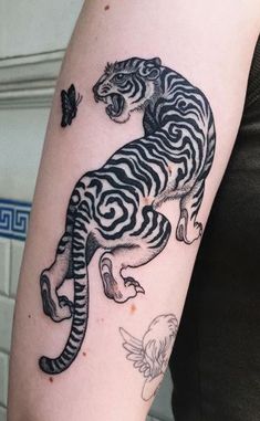 a black and white tiger tattoo on the right arm, with butterflies flying around it