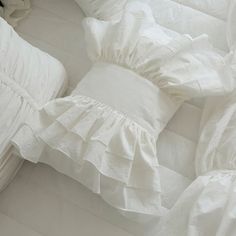 white bedding with ruffles and pillows on it