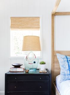 a bed room with a neatly made bed and a lamp on top of the night stand