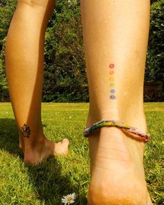 a person's bare foot with a colorful bracelet on their left ankle and flower in the grass