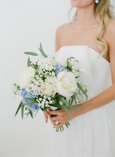 a woman holding a bouquet of white and blue flowers