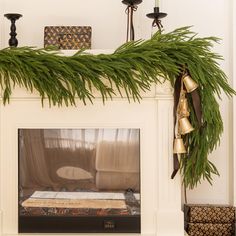 a fireplace decorated with evergreen branches and bells