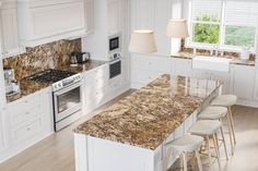 a kitchen with marble counter tops and white cabinets