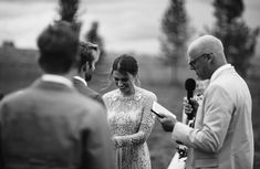 a man and woman standing next to each other in front of a microphone at a wedding