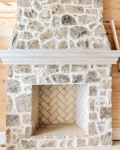 a stone fireplace in a room with wood paneling