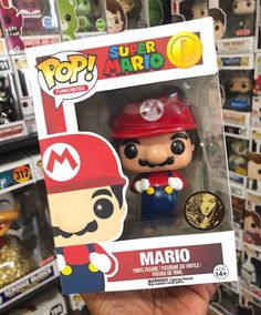 a hand holding up a box with a mario pop vinyl figure in it's packaging