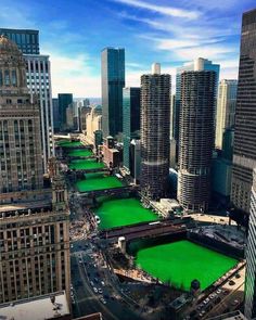 a city with lots of tall buildings and green grass on the ground in front of them