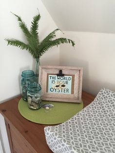 there is a vase with some plants on the table next to it and a sign that says the world is your oyster